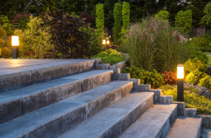 Landscaped Garden with Concrete Stairs and Decorative Illumination Closeup of Concrete Stairs in Beautifully Landscaped Backyard Garden Planted with Various Shrubs and Bushed and Decorated with Outdoor Garden Lights.